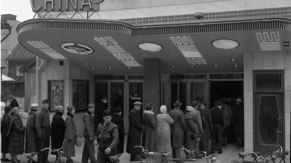 9 mars 1957. Chinabiografen i Lindstens nya hus på Ågatan i Linköping invigs. Till höger restaurang Maxim. Vilken film de köar för att se? Alfred Hitchcooks svarta komedi "Ugglor i mossen" från 1955.