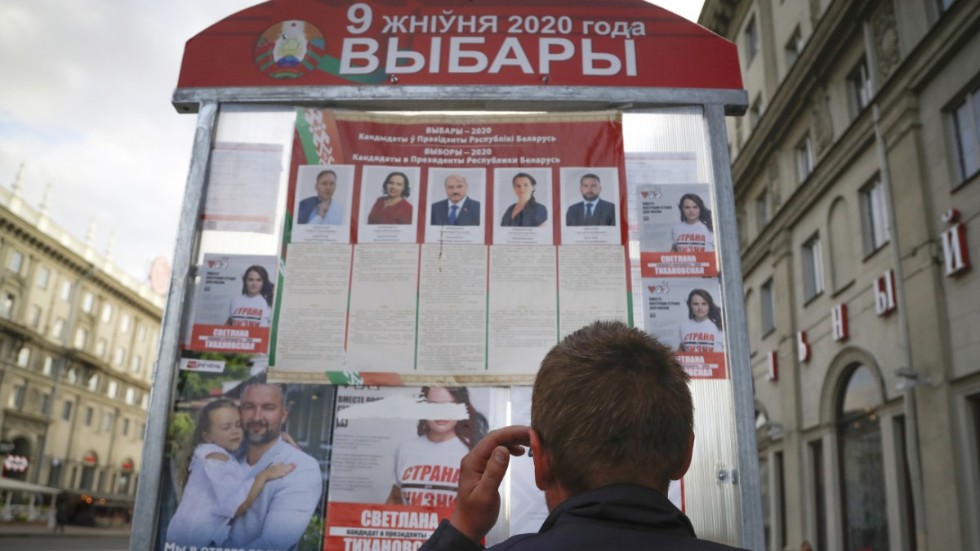 En man står framför en valaffisch i Minsk, Belarus.