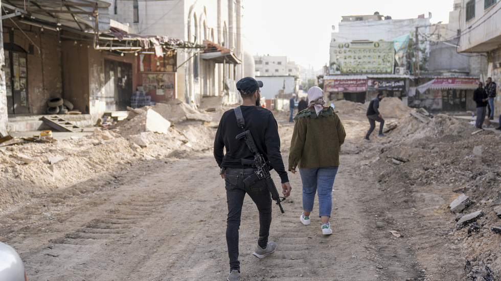 En beväpnad palestinier går omkring på en väg i Jenin som tog stor skada vid helgens israeliska operation där.