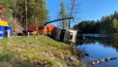 BILDERNA: Här bärgas timmerbilen efter olyckan · Körde av vägen och ner i sjö