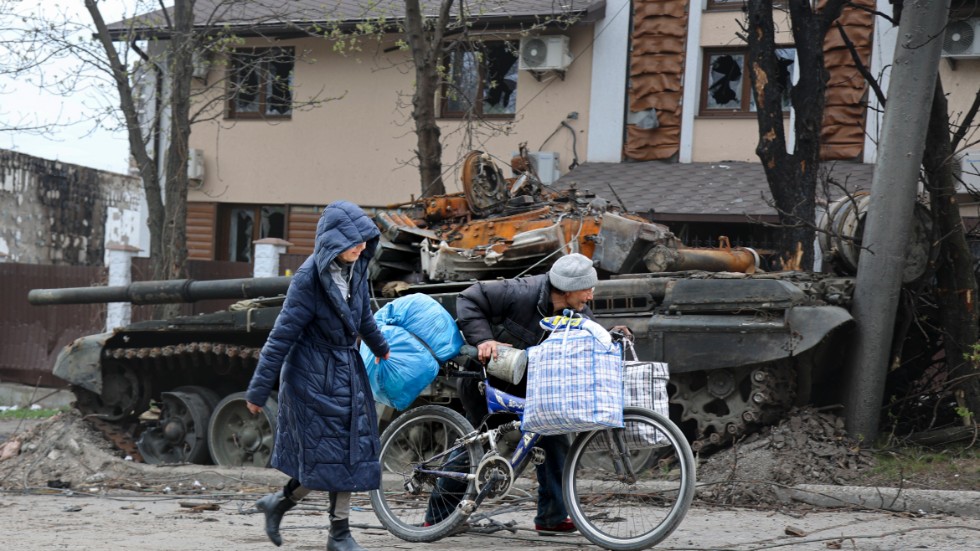 Lokalbor i Mariupol går förbi en förstörd stridsvagn.