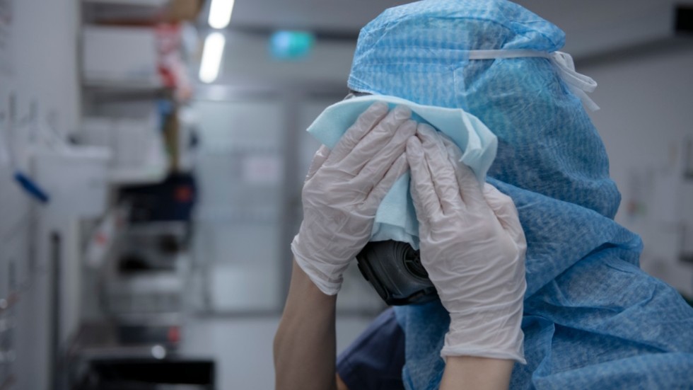 En sjuksköterska tvättar sin skyddsmask efter ett arbetspass på intensivvårdsavdelningen på Södertälje sjukhus under pandemins första år 2020.