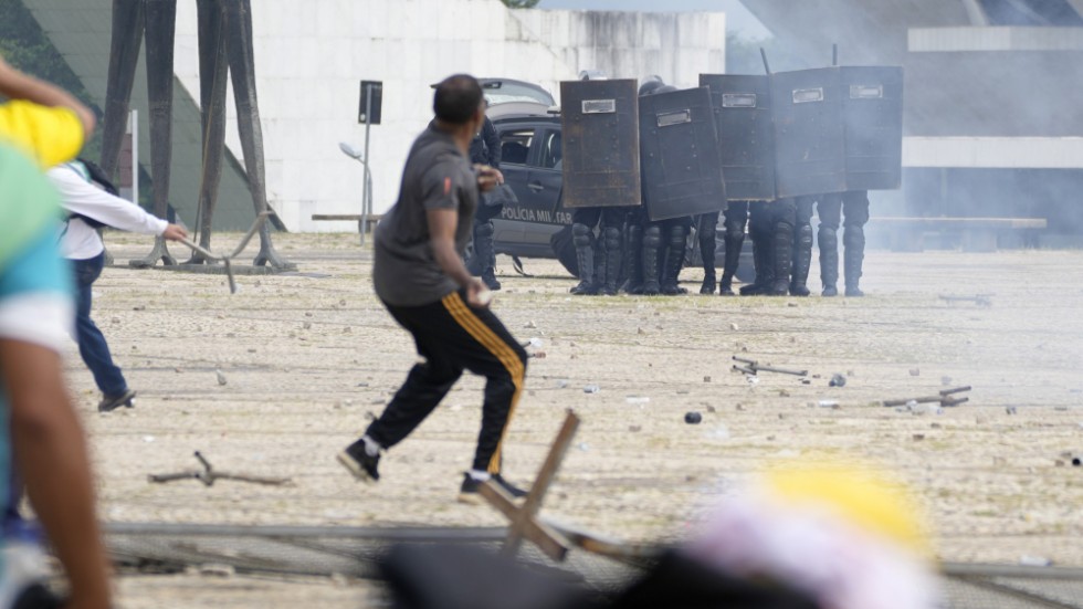 Bolsonaroanhängare drabbar samman med polis under stormningen av presidentpalatset Planalto i söndags.