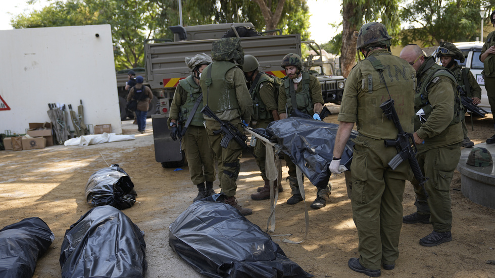 Israeliska soldater bär ut ett av offren för Hamas massaker i den israeliska kibbutzen Kfar Azza.