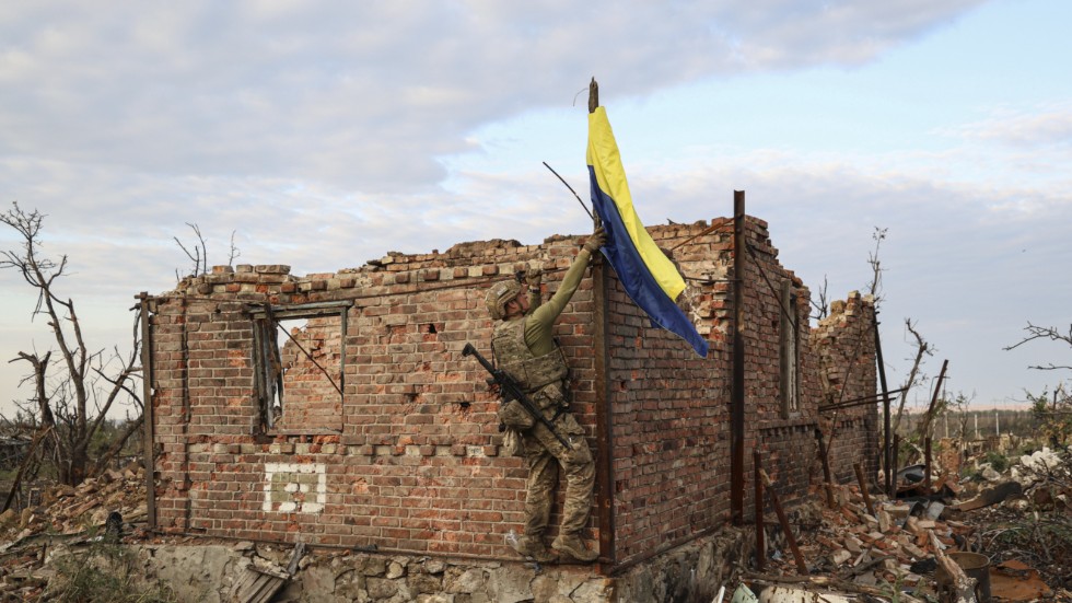 En soldat hänger upp en ukrainsk flagga i närheten av byn Andriivka som Ukraina nyligen sade sig ha intagit.