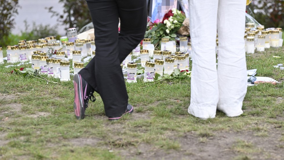 Blommor och ljus vid den plats vid Mälarhöjdens IP i Stockholm där en ung man blev skjuten till döds i onsdags. Fotografiet på 18-åringen är pixlat.