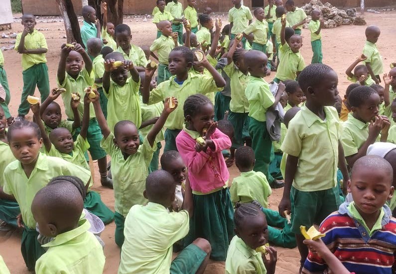 Fruktstund i det fria. Stor glädje bland barnen i sina gröna skoluniformer.