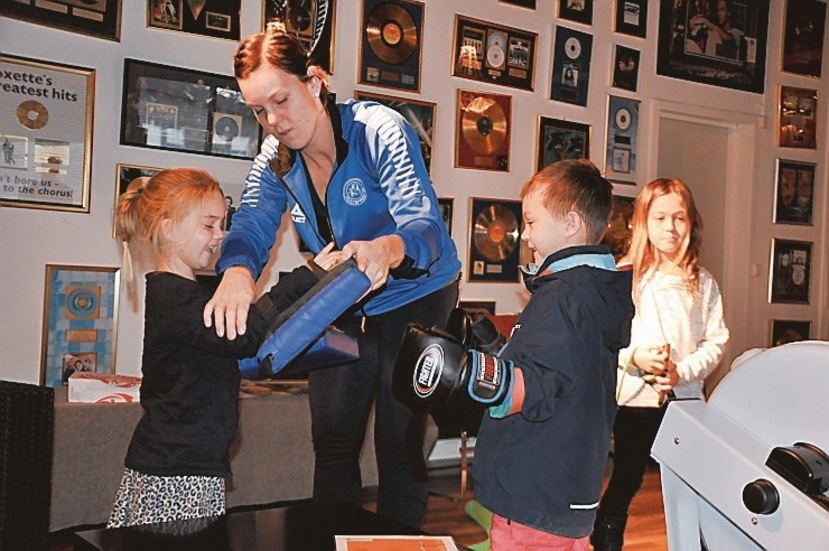 Här instruerar Caroline Phalén barnen Gusten Fogis och Alva Phalén hur man använder boxningsredskapen.