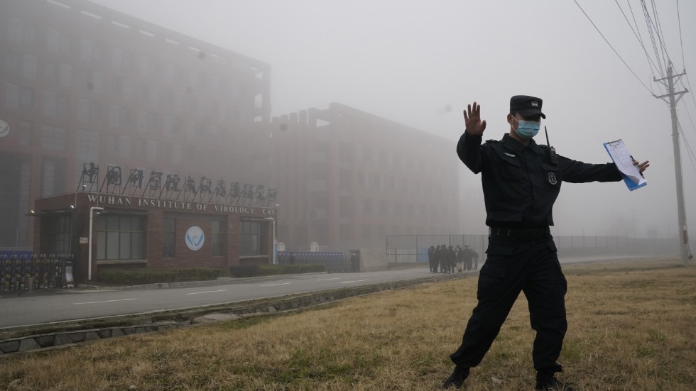 En säkerhetsvakt motar bort journalister från det laboratorium i Wuhan, där sars-cov2-viruset uppstod enligt vissa teorier. Arkivbild.