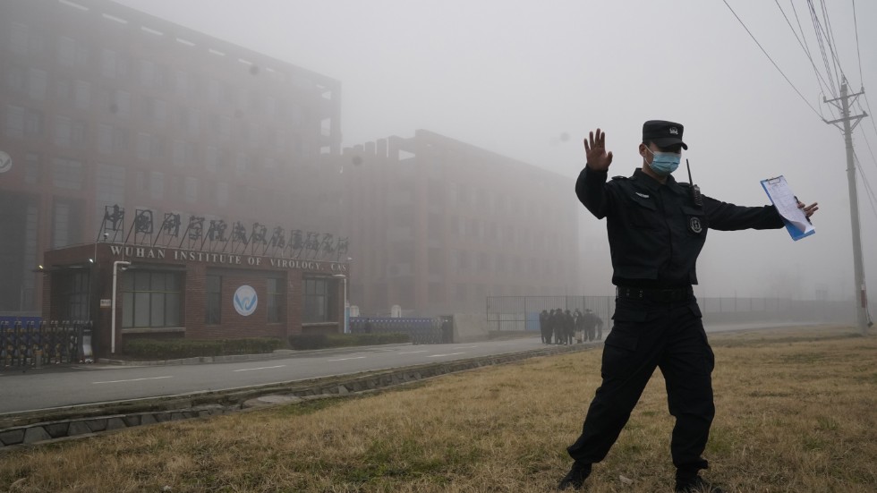 En säkerhetsvakt motar bort journalister från det laboratorium i Wuhan som enligt vissa teorier pekats ut som ursprunget till coronapandemin. Arkivbild.