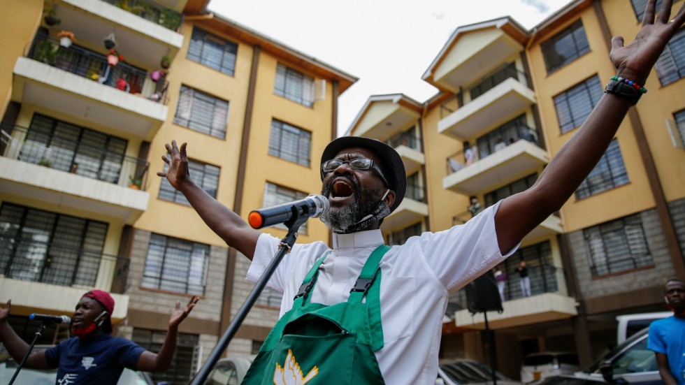 Paul Machira sjunger och predikar för boende i ett lägenhetsområde i den kenyanska huvudstaden Nairobi. Runt om honom sjunger och dansar barn på sina balkonger.