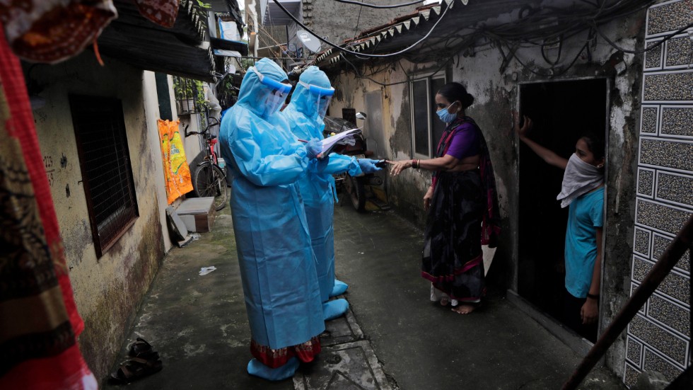 Indiska hälsoarbetare covid-screenar boende i ett fattigt område i staden Bombay (Mumbai).