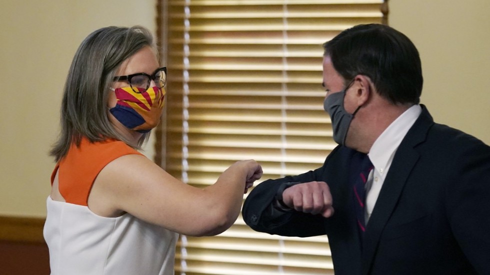Arizonas delstatssekreterare, demokraten Katie Hobbs, nuddar armbåge med guvernören tillika republikanen Doug Ducey. De är överens om att valet där gått rätt till.