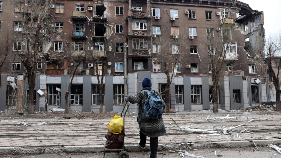 En boende i den belägrade ukrainska hamnstaden Mariupol tittar på en av de byggnader som förstörts sedan Rysslands anfallskrig inleddes den 24 februari.