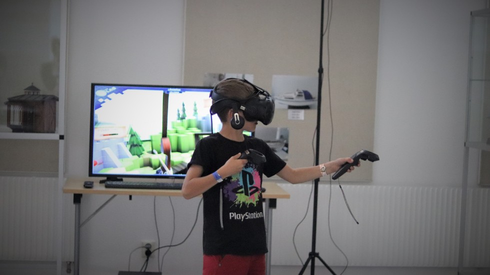 Alex Dahlgren, 11, testar VR på biblioteket. På skärmen bakom honom kan besökarna följa det han ser i sina glasögon.