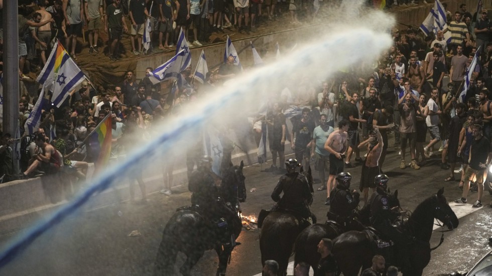 Polis med vattenkanoner skingrar demonstranter i Tel Aviv på måndagen.