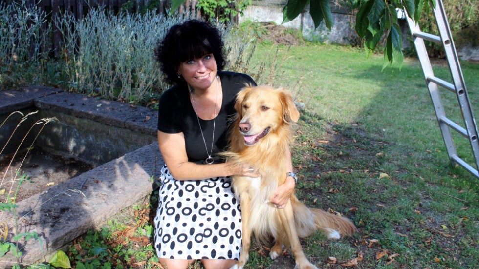 Sandra mår bra av att ha djuren omkring sig. Här i trädgården med hunden Chino.