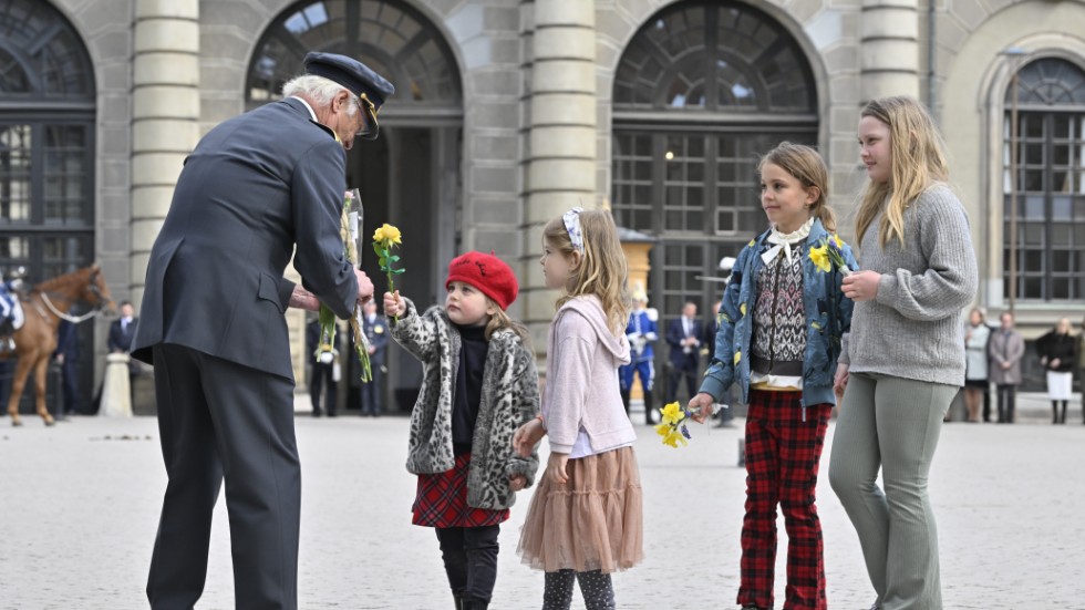 En grupp barn uppvaktar kungen med blommor.