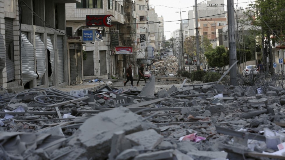 Människor inspekterar resterna av en bombad kommersiell by7ggnad och en vårdklinik i staden Gaza.