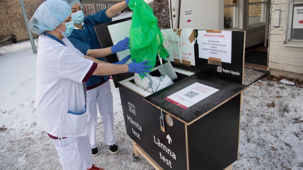 Undersköterskan Seema Gul, närmast i bild, fyller på förpackningar med covid-19-test i självbetjäningslådan utanför lasarettet i Enköping. På måndagen hämtades 840 tester ur lådan.