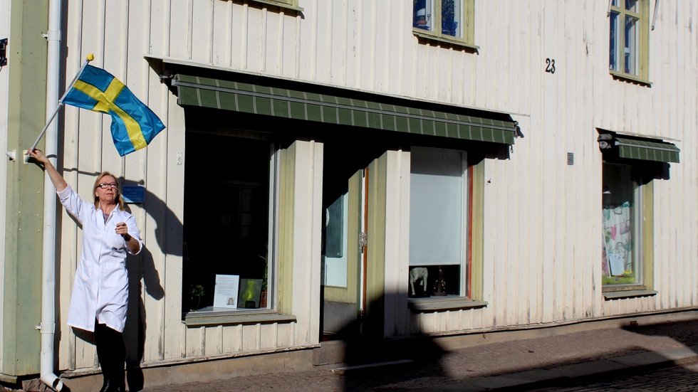 Ann-Marie Brushane hänger upp flaggan utanför CHG Galleri och Ateljé på Storgatan i Vimmerby.