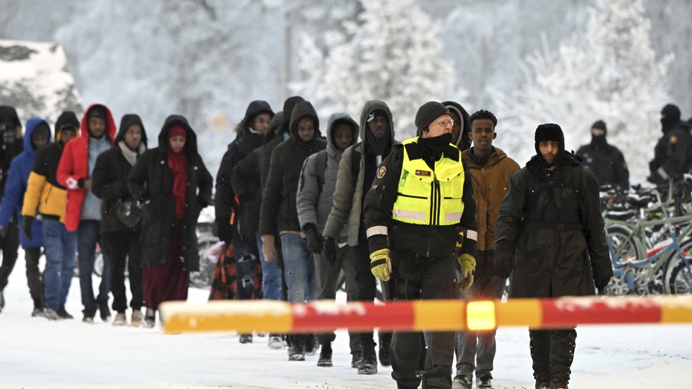 Finska gränsvakter eskorterar migranter vid gränsövergången i Salla på torsdagen.