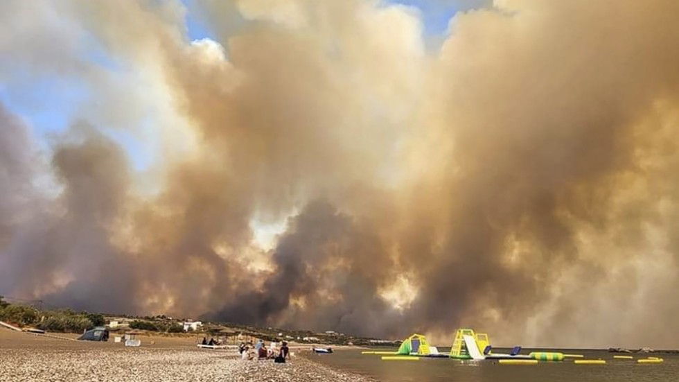Rökmoln stiger över en strand på Rhodos under lördagen.
