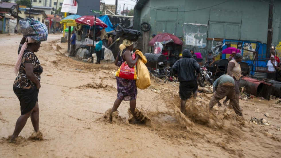 Gatuförsäljare vid en översvämmad väg Haitis huvudstad Port-au-Prince i söndags.