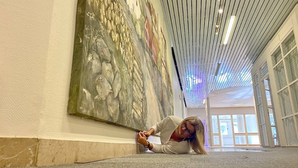 Vad gör man inte för konsten? Annie Wårhem lägger sig på golvet i den före detta banklokalen på Torggatan för att montera ner en stor målning över Bersbo. 