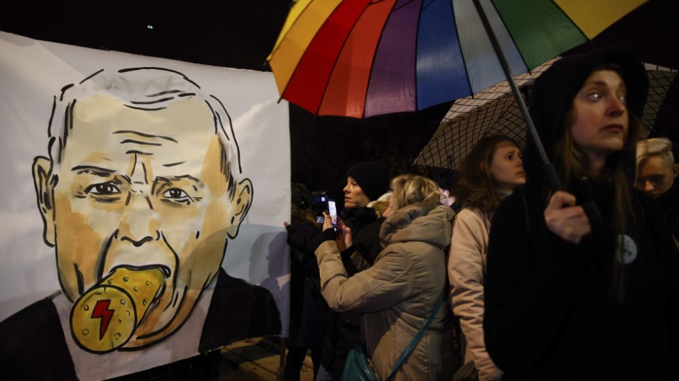 Warszawabor protesterar framför Jaroslaw Kaczynskis hus den 28 november, med en karikatyr på partiledaren där en kork pluggar igen hans mun. Kaczynski leder regeringspartiet Lag och rättvisa.