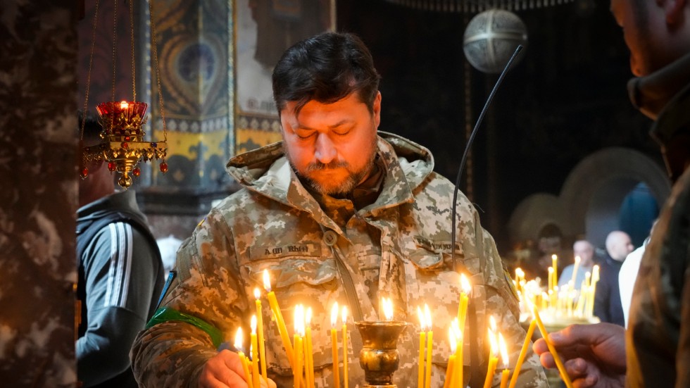 En ukrainsk soldat tänder ett ljus i Volodymyskyj-katedralen i Kiev under det ortodoxa påskfirandet på söndagen.