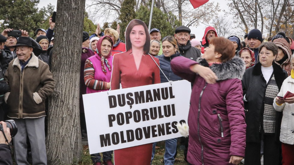 En kvinna slår en kartongmodell av Moldaviens västvänliga president Maia Sandu med en skylt som lyder "Det moldaviska folkets fiende". Bilden är tagen under en protest i november initierad av partiet Shor. Arkivbild.