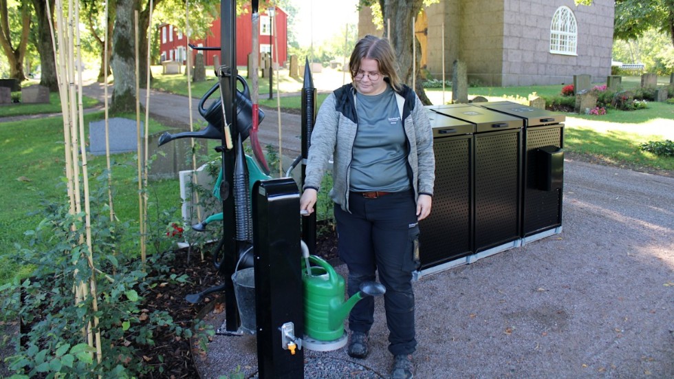 Kyrkvaktmästaren Anna Schörling visar den ergonomiskt utformade vattenposten vid en av de nya miljöstationerna.