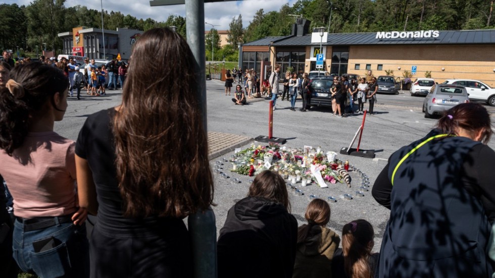 Folk samlas vid blommorna och ljusen på rastplatsen där en tolvårig flicka sköts ihjäl vid en bensinmack i Botkyrka, söder om Stockholm natten mot söndagen.