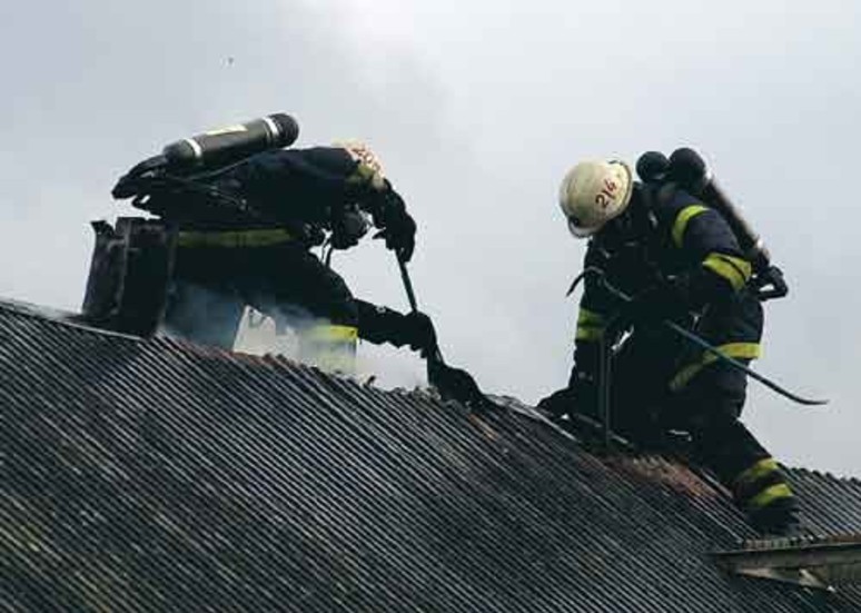 Brandmännen hade ett tufft jobb att bryta upp plåttaket på uthuset. Men det var nödvändigt för att komma åt brandhärdarna därunder. Blåsten gjorde det inte lättare att sitta på taket heller.