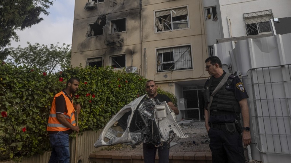 Förstörda hushållsapparater bärs ut från det träffade huset i israeliska Ashkelon.