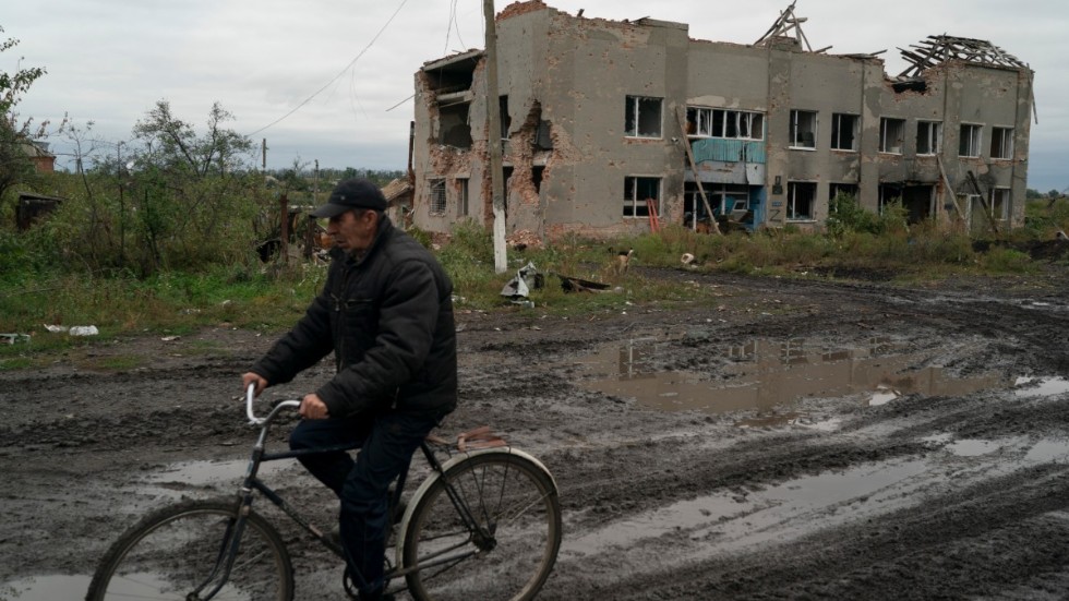 En man cyklar förbi en byggnad som tidigare ockuperades av ryska styrkor. Bild från Charkivregionen den 13 september.