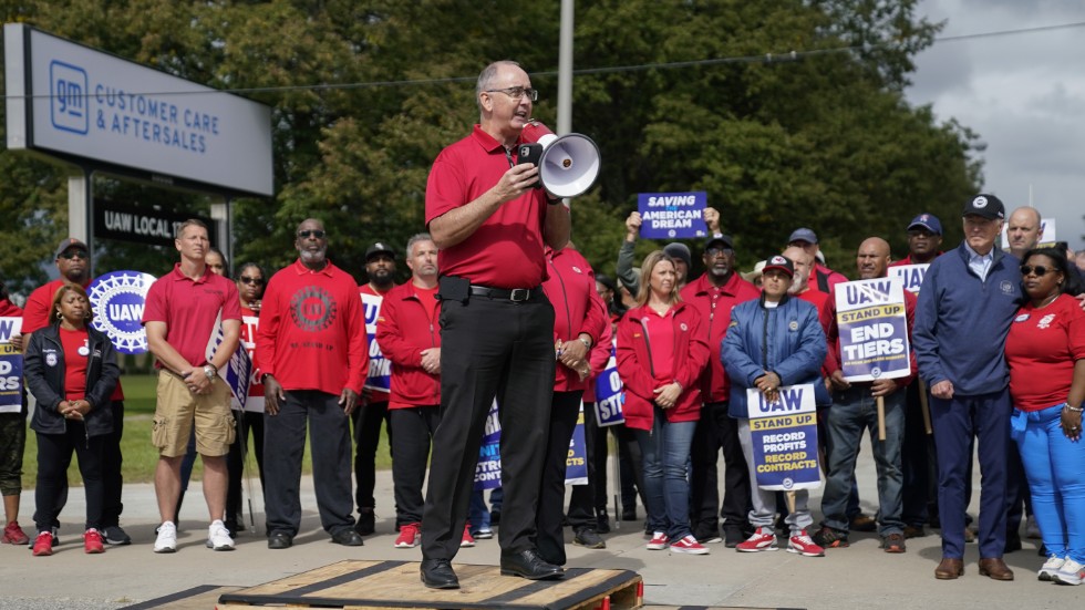 UAW:s ordförande Shawn Fain leder strejkprotester, med bland andra president Joe Biden som åhörare.