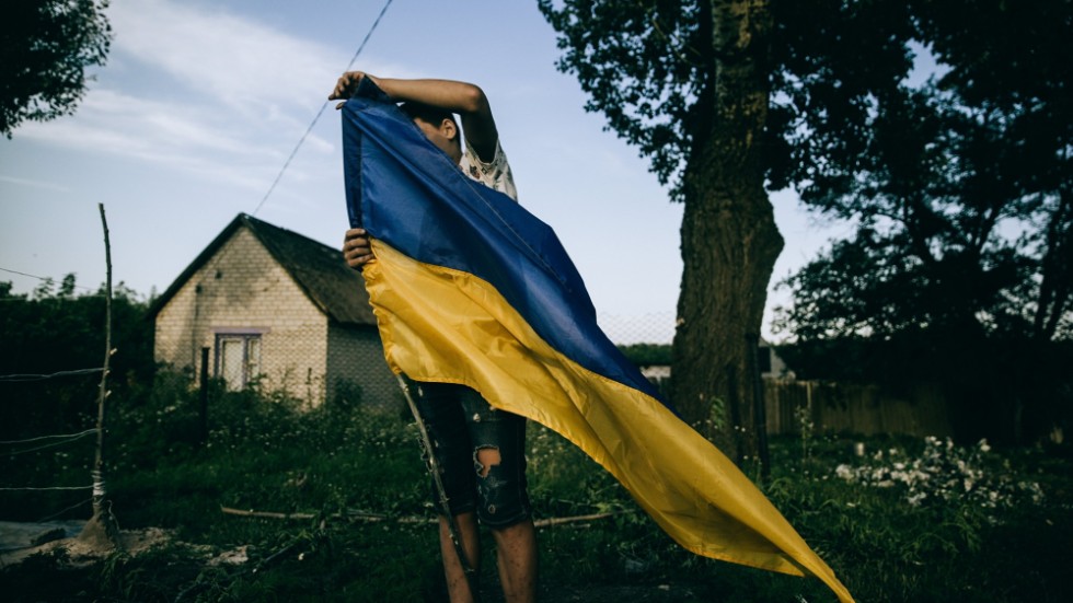 Ett barn sätter upp en ukrainsk flagga som "checkpoint" i byn Zelene i Charkiv-regionen.