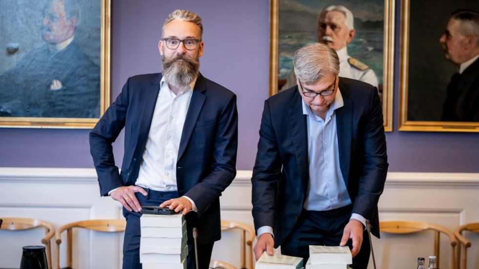 Ole Birk Olesen, Liberal Alliance, och Peter Seier Christensen, Nye Borgerlige, med minkkommissionens nio band stora rapport.
