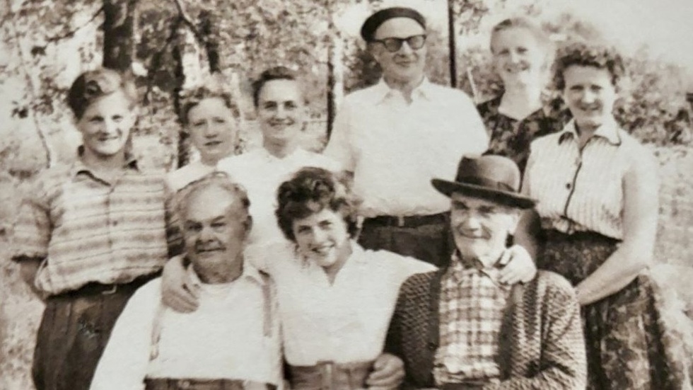 Bilden är från husets 50-årsfirande år 1957. På bilden syns bildhuggaren Theodor Karlsson, grannen Karl Wilhelmsson, och Theodors barnbarn Thomas, Margareta, Dorothy, Kurt, Daisy, Liselott och Majvor.