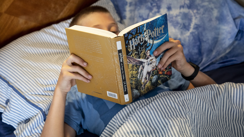 Ett barn läser en bok i en säng. Utmaningen är att få unga att fortsätta läsa i tonåren. Arkivbild.