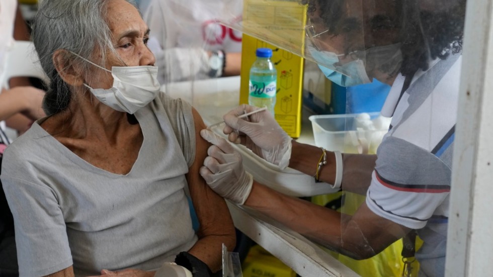 I Filippinerna håller nio miljoner människor på att vaccineras, efter att den nya omikronvarianten av coronaviruset upptäckts. På bilden får en kvinna sin spruta i staden Quezon.