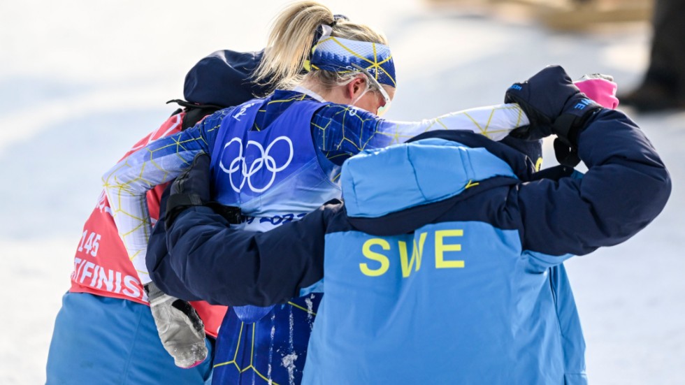En talade bild för Frida Karlssons OS. Skidstjärnan får hjälp av svenska ledare att ta sig ut från målområdet efter kollapsen på 10 kilometer.