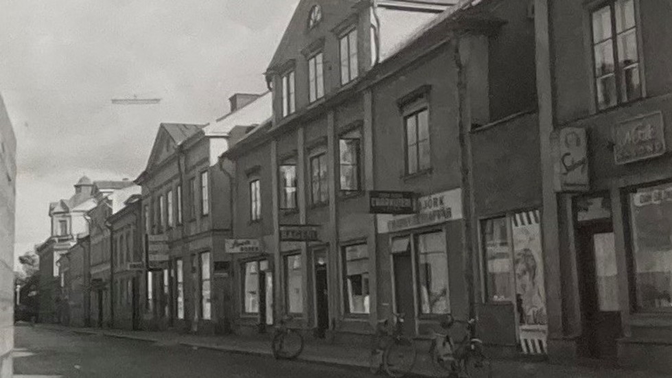 De två stora byggnaderna mitt i bilden låg båda på den stora fastigheten Storgatan 14. Gathusen innehöll såväl butiker som bostäder. I gårdens uthus fanns bland annat hantverkslokaler. Bild från september 1955.