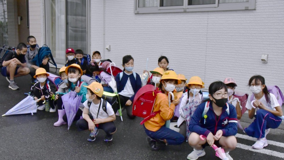 Barn på väg till skolan i Misawa i den japanska prefekturen Aomori tar skydd efter rapporterna om den nordkoreanska robotuppskjutningen.