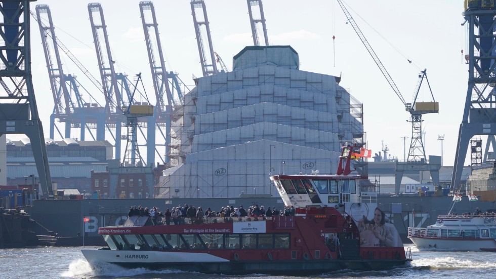 Den 156 meter långa lyxjakten Dilbar ligger på varv i Hamburg, här inplastad bakom turistbåten. Arkivbild