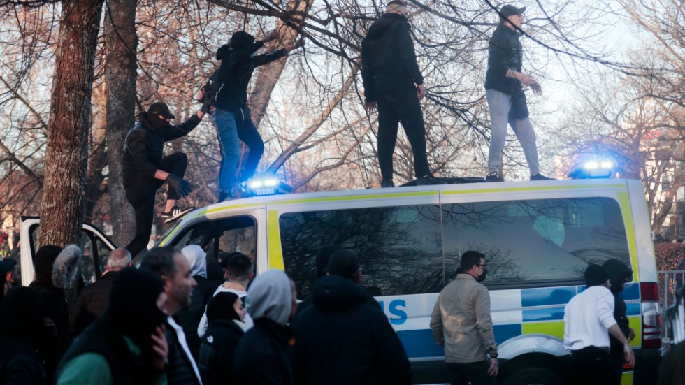 Motdemonstranter klättrar upp på en polisbuss i Sveaparken i Örebro.