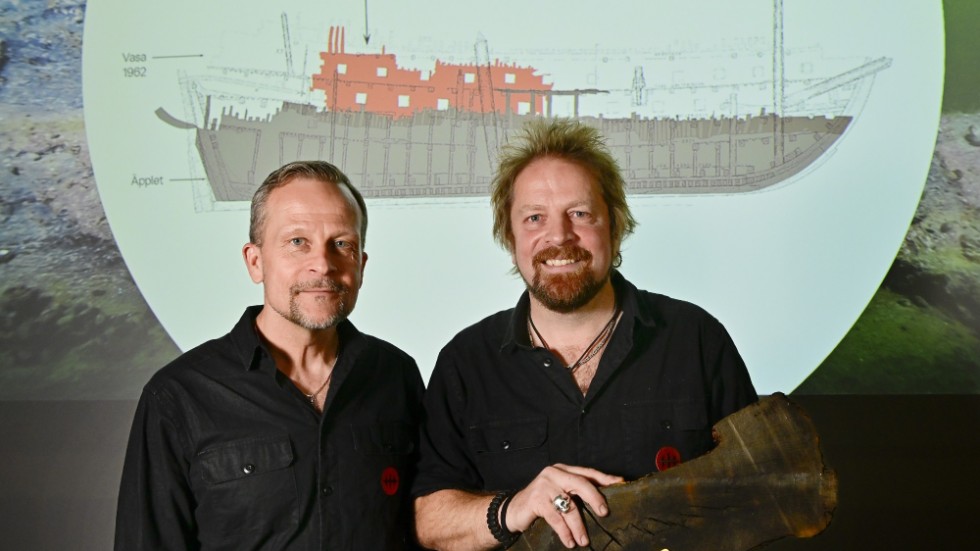 Dykarna Patrik Höglund och Jim Hansson, marinarkeologer på Vrak, håller i en bärgad del av skeppet.