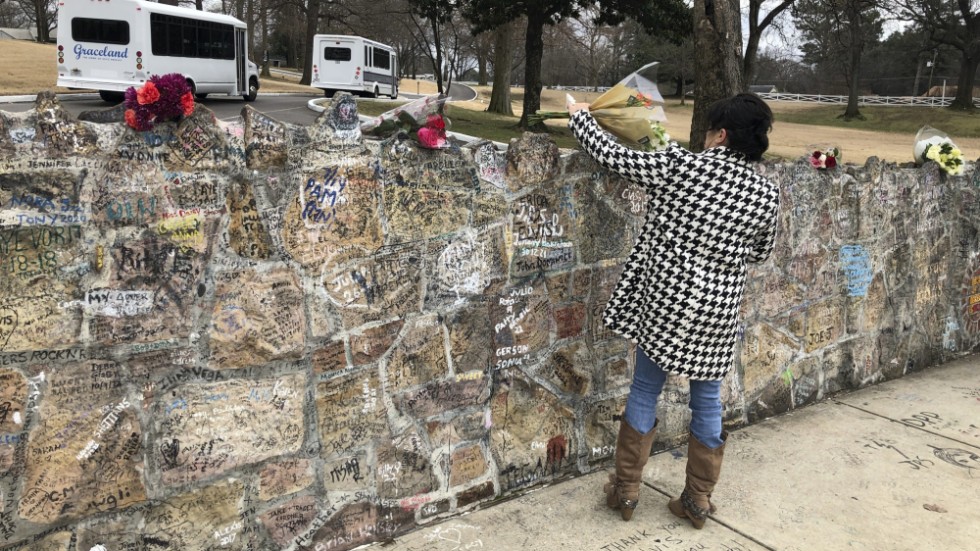 Ett fan placerar en blombukett vid Graceland i Memphis.